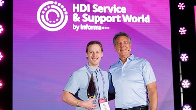 Nathan Lantaigne-Goetsch standing on stage with Kirk Weisler accepting the HDI Award for Best Service & Support Technician