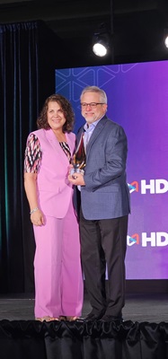 Doug Tedder, HDI's 2025 Lifetime Achievement Award Winner accepting a trophy from Rae Bruno, the 2024 Lifetime Achievement winner